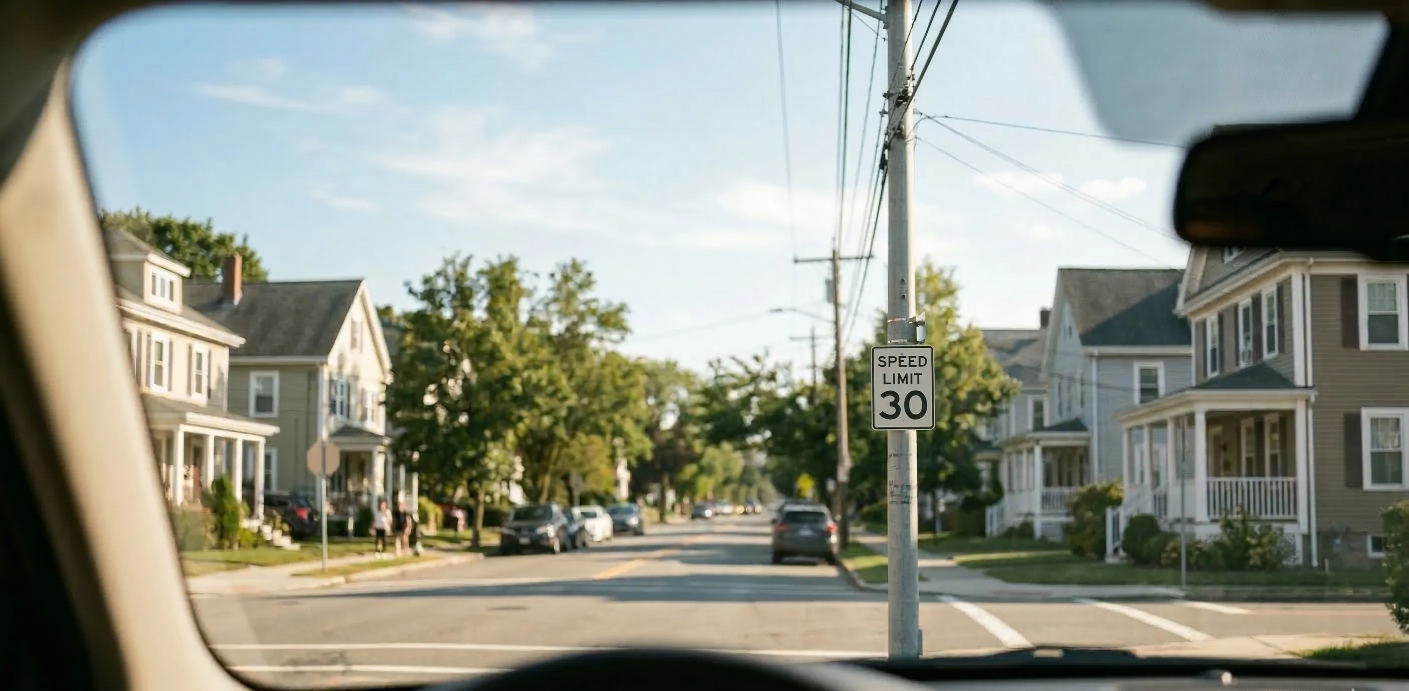View from car approaching intersection with speed limit sign — road signs become unreadable with increasing myopia